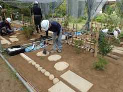 完成直前の仕上げ作業で飛石の掃除をする学生