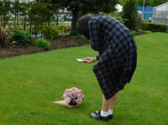 ラウンドアレンジメントの写真を芝生の上で撮る学生