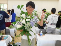 完成した花束をうれしそうに掲げる学生