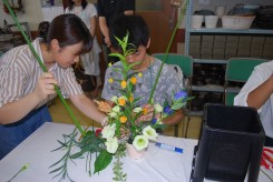 オープンキャンパスに来た高校生にアレンジメントを指導する花き装飾コースの学生