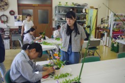 オープンキャンパスに来た高校生にアレンジメントを指導する花き装飾コースの学生