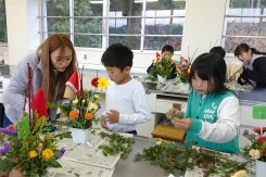 クリスマスフラワーアレンジメントを小学生に指導する学生の様子