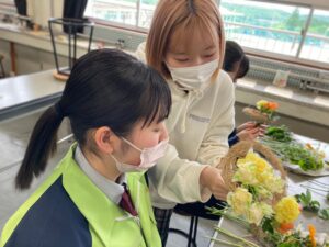 花束制作の指導を高校生にする学生の様子