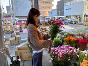 卸売市場で切り花を選ぶ学生ら