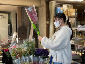 卸売市場で切り花を選ぶ学生ら