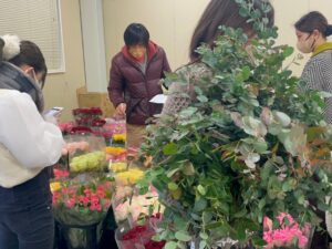 卸売市場で切り花を選ぶ学生ら