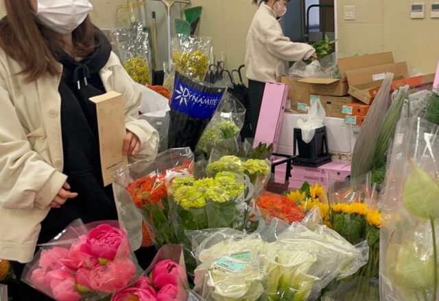 卸売市場で切り花を選ぶ学生ら